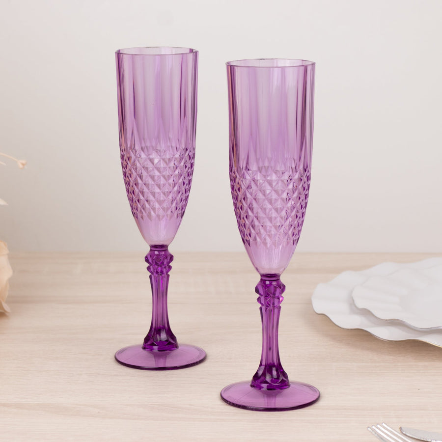 Purple crystal champagne flutes with intricate design, set on a light wooden surface.