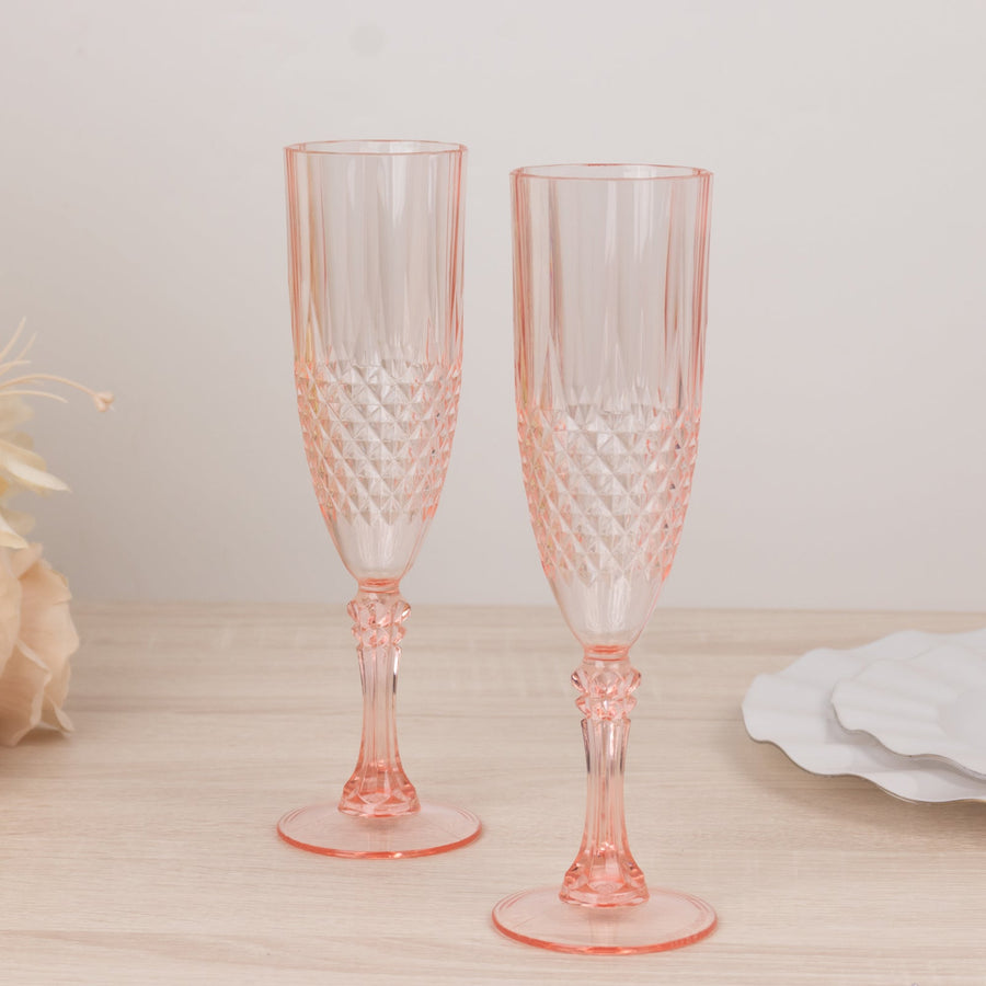 Two elegant pink crystal champagne flutes on a wooden surface.
