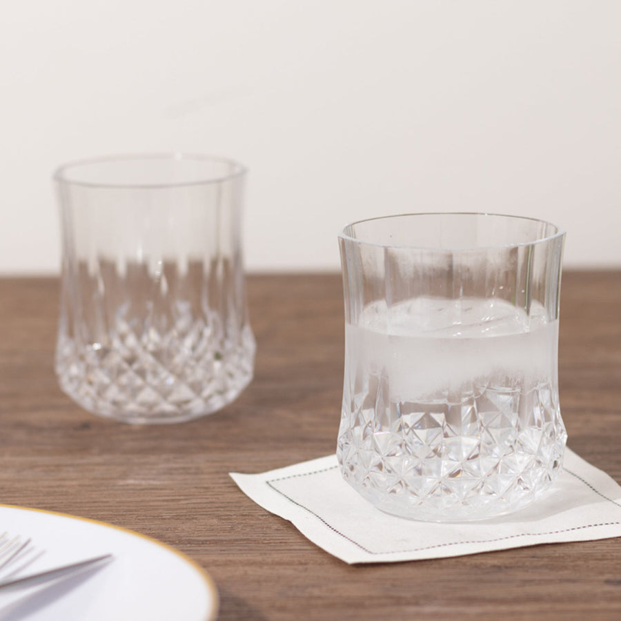 Crystal clear tumbler glasses on a wooden table.