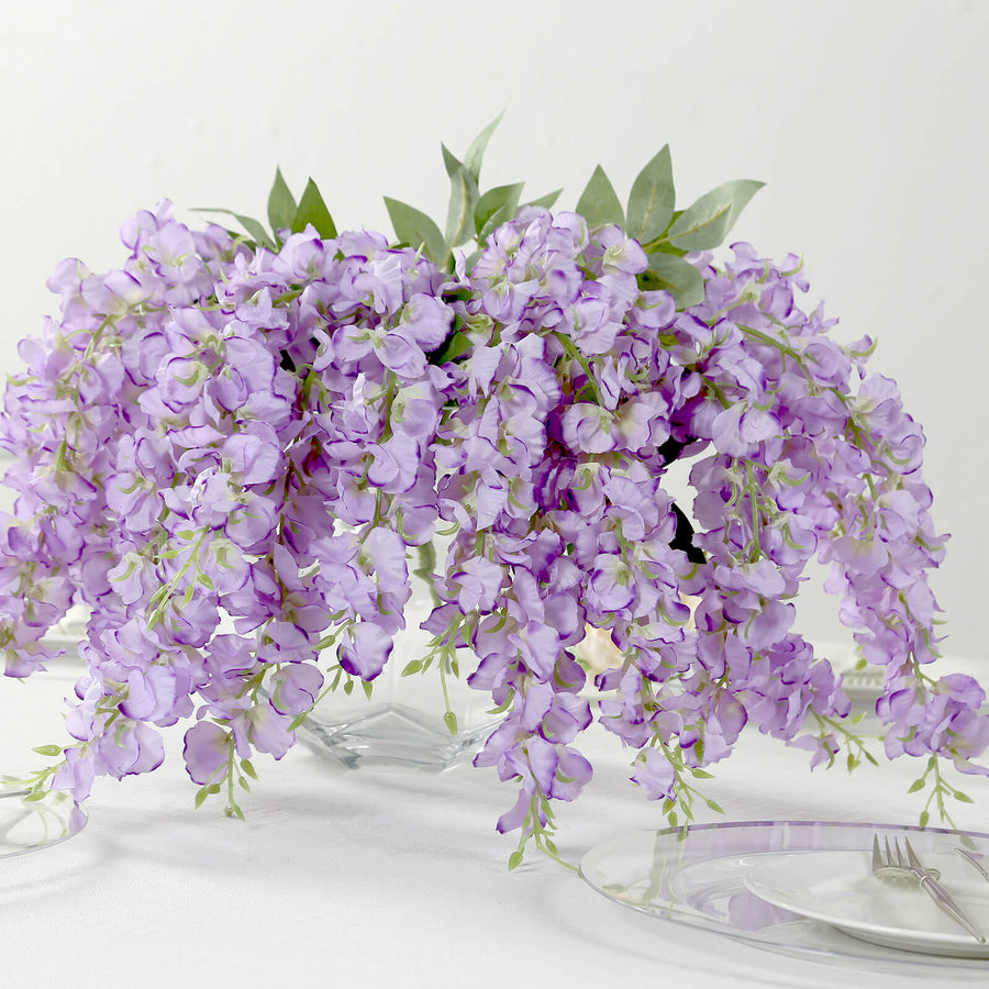 Artificial purple wisteria floral arrangement in a glass vase