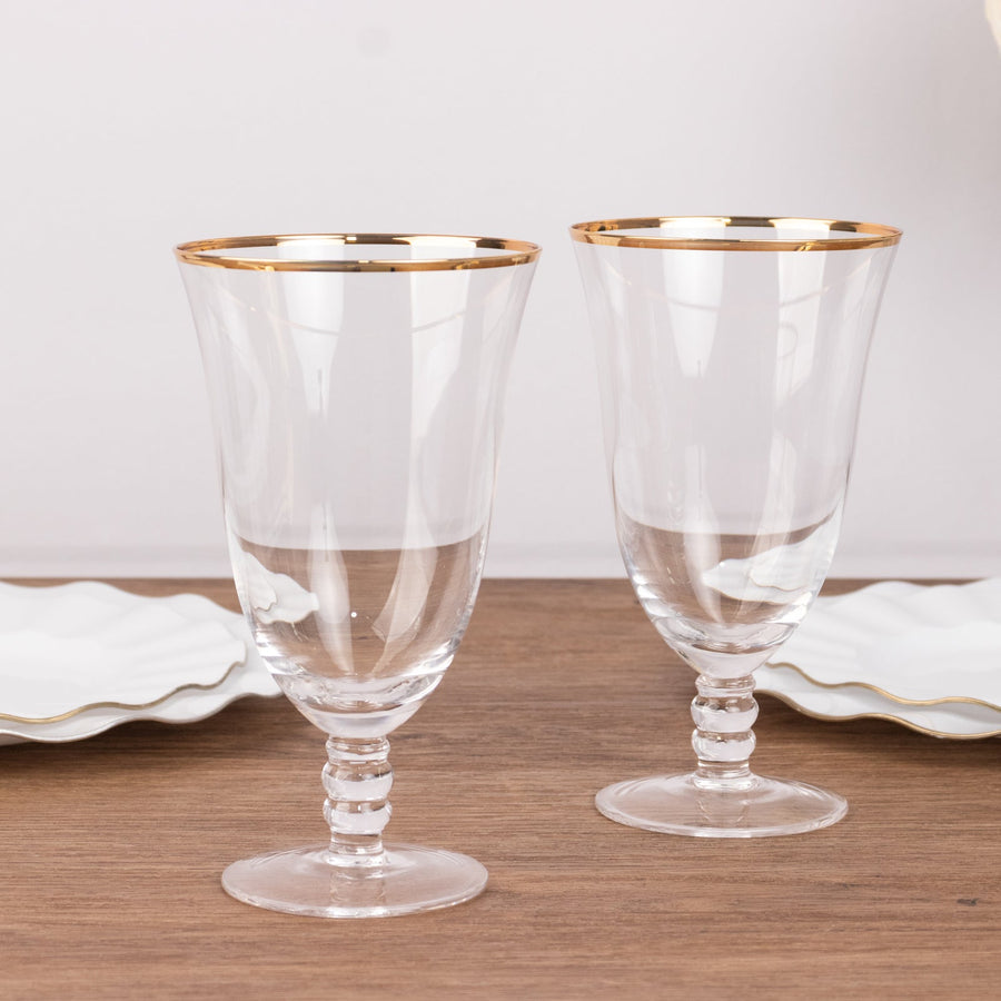 Elegant crystal glasses with gold rim on a wooden table.