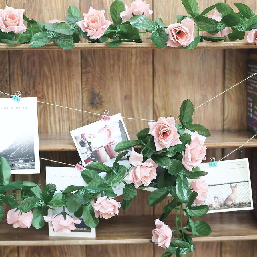 Pink artificial roses with greenery on a rustic wooden shelf displaying photos.