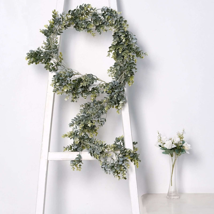 Artificial greenery wreath on a white ladder with floral vase