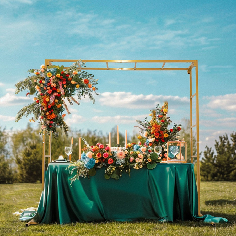 Elegant outdoor wedding decor with vibrant flowers and a gold arch.