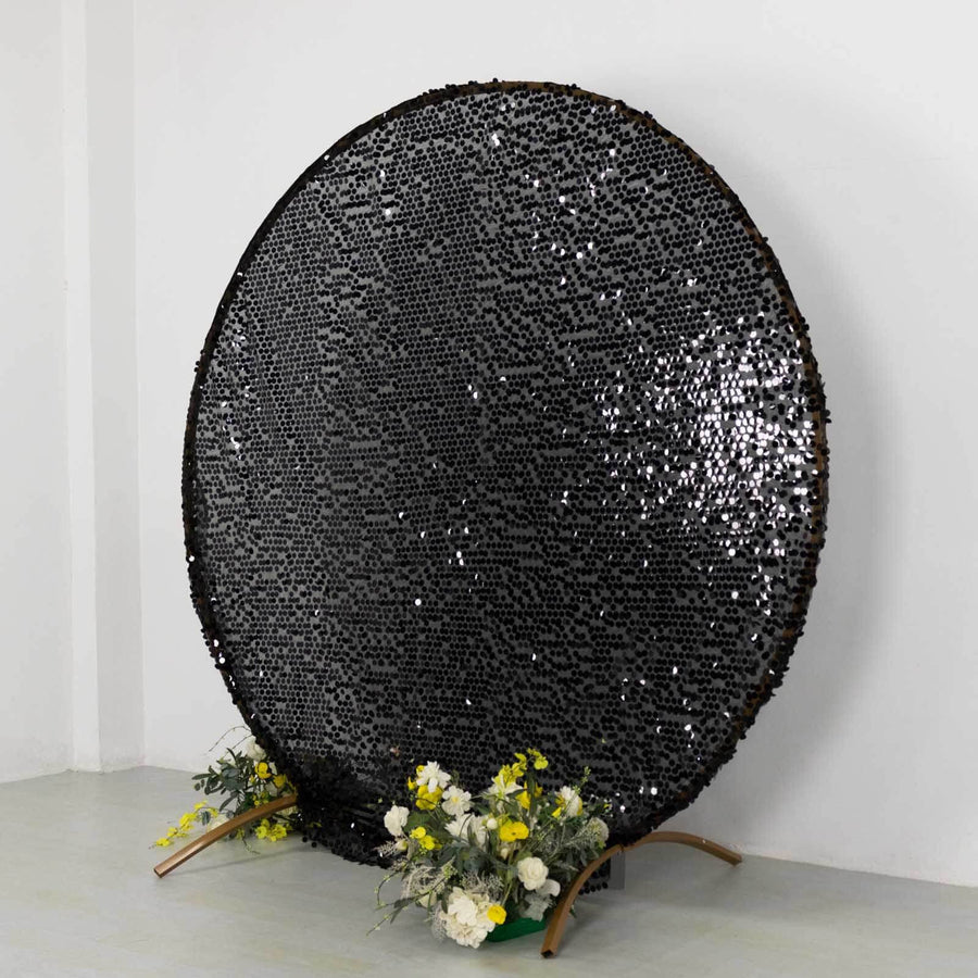 Black decorative round mirror with a floral base arrangement.
