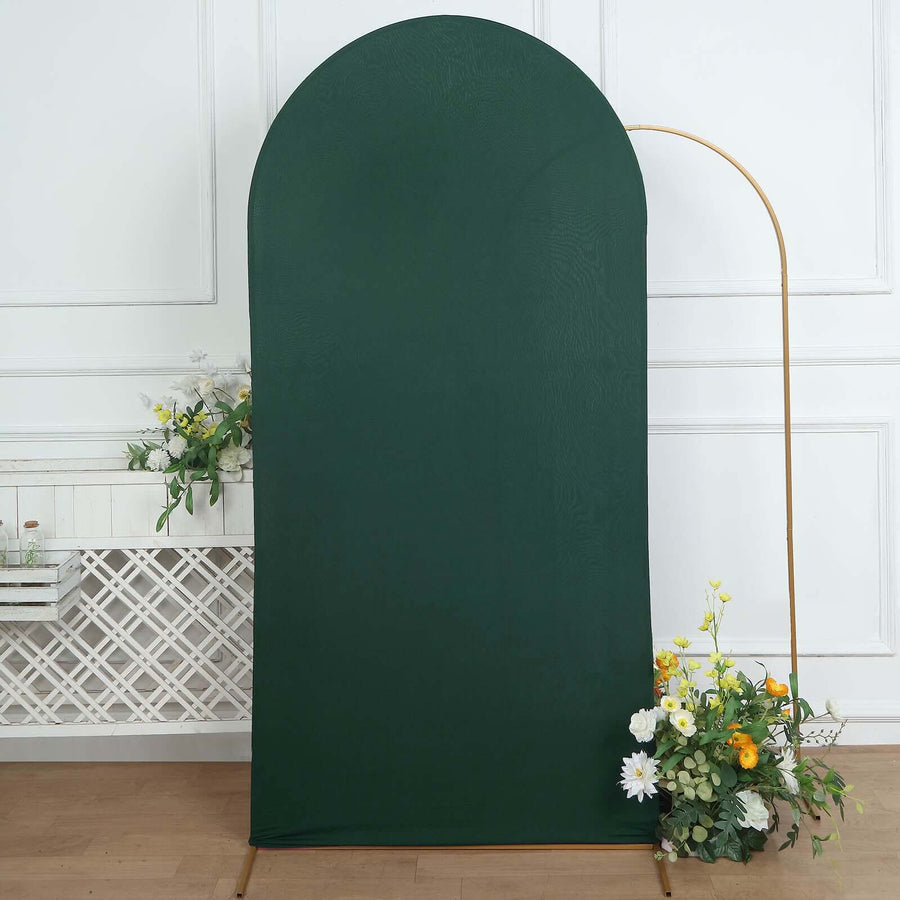 Green fabric backdrop with a gold stand and floral arrangement.