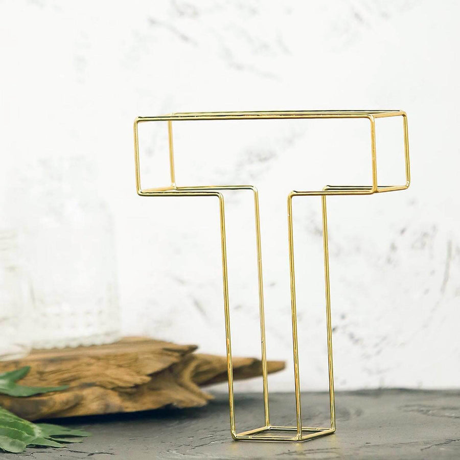 Gold wire letter T sculpture on a textured surface.