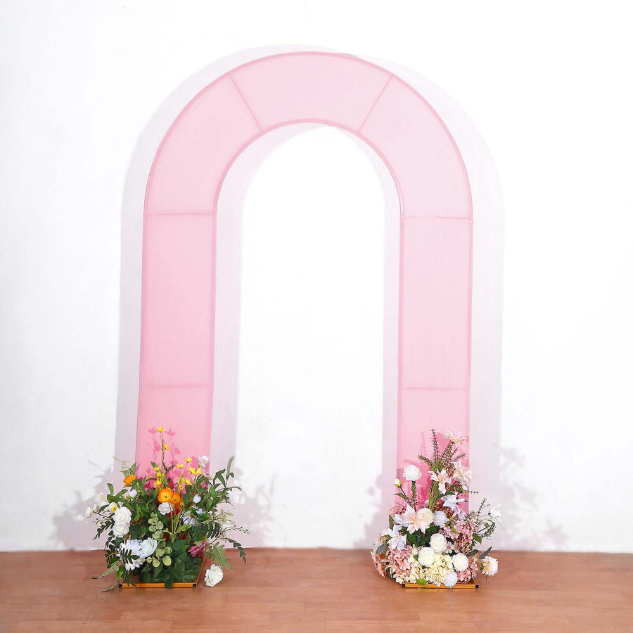 Pink arch with floral arrangements at the base