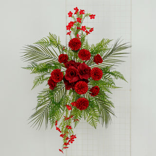 Red floral arrangement with roses, dahlias, and greenery on a white backdrop.