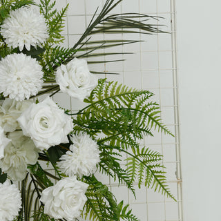 White floral arrangement with roses and ferns on a grid backdrop.