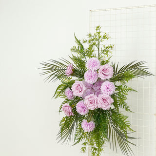 Purple roses and greenery arrangement on a grid backdrop.