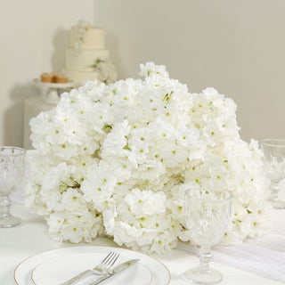 White floral centerpiece on a dining table with glassware.