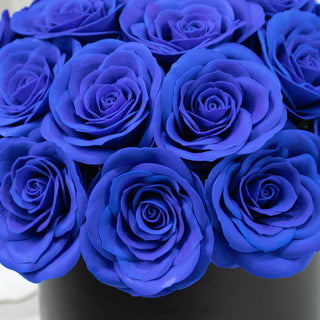 Blue roses in a black round box, showcasing vibrant petals and elegant arrangement.