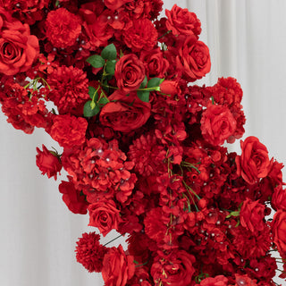 Vibrant red floral arrangement with roses and blooms against a neutral background.