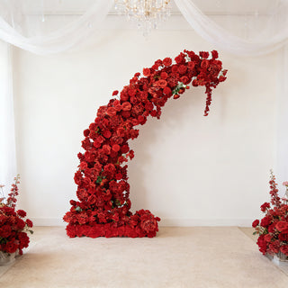 Red floral arch decor for events, surrounded by matching flower arrangements.