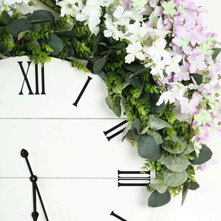 Floral wall clock with white background and greenery accents.