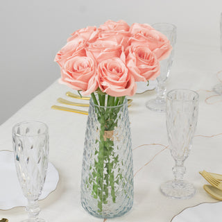 Pink roses in a crystal vase on a dining table setting.
