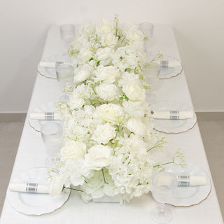 Elegant white floral table centerpiece with glassware and plates.