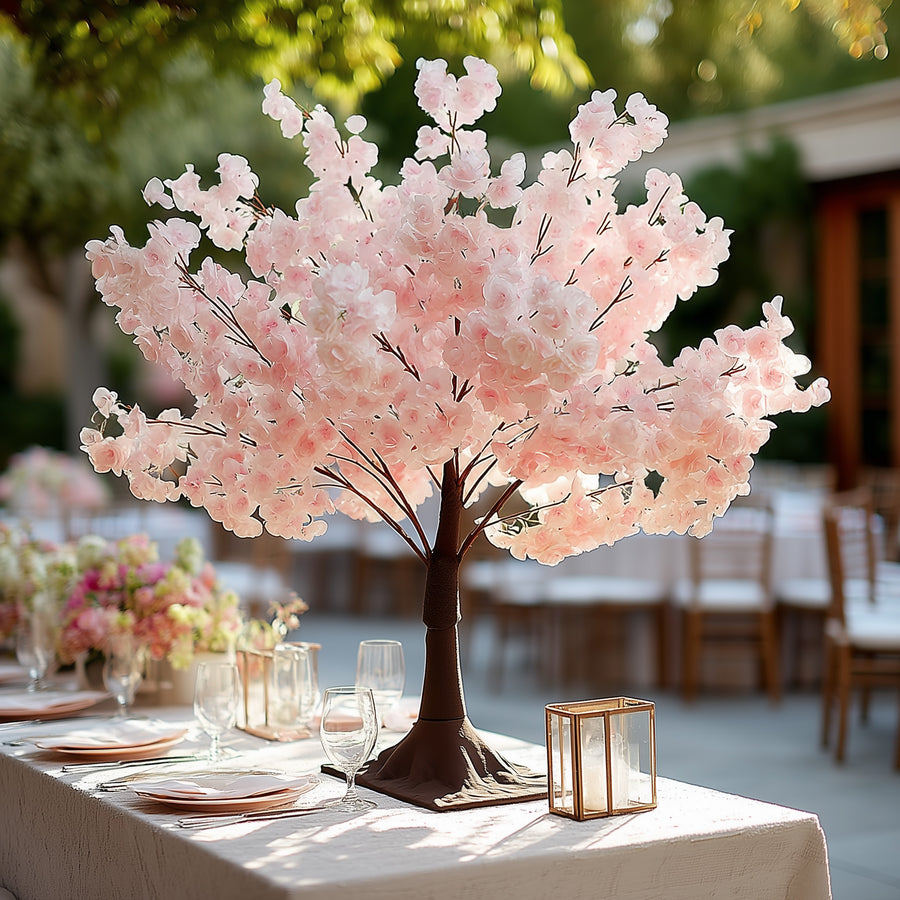 Pink cherry blossom tree centerpiece for elegant dining table setting.