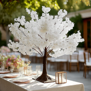 White flowering tree centerpiece for elegant dining setup.