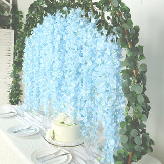 Blue floral backdrop with greenery for event decoration and cake display.