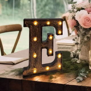 Decorative marquee letter "E" with lights, set on a rustic table.