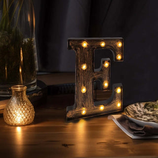 Decorative light-up letter "E" on a wooden table with warm lights.
