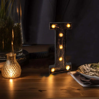 Illuminated wooden letter "I" decorative sign with lights on a wooden table.