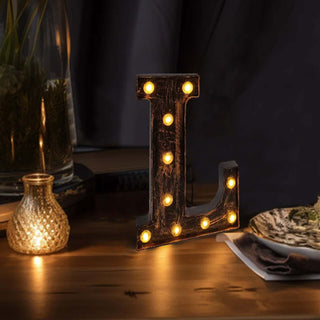 Decorative marquee letter "L" with lights on a wooden table.