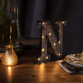Decorative light-up letter "N" with a rustic finish and warm bulbs.