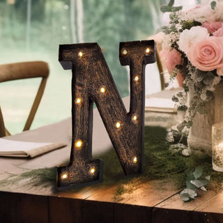 Decorative vintage marquee letter "N" with lights on a styled table setting.