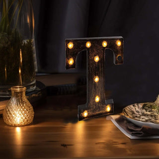 Vintage marquee letter "T" with warm lights on a wooden table.