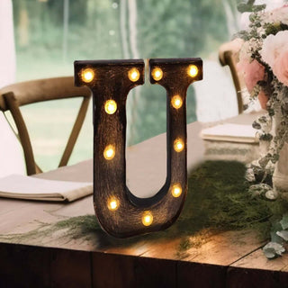 Decorative marquee letter "U" with lights on a rustic table setting.