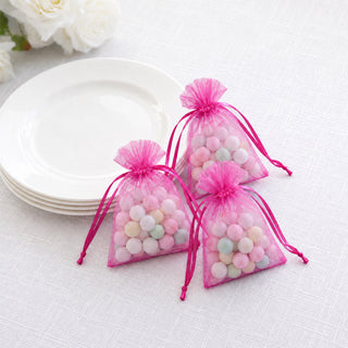 Pink organza gift bags with pastel candy beads on a white plate