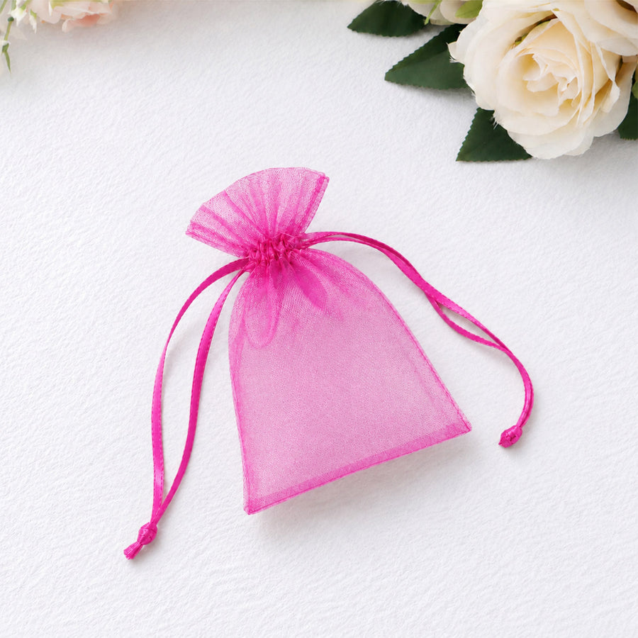 Pink organza drawstring pouch with ribbon, on white fabric