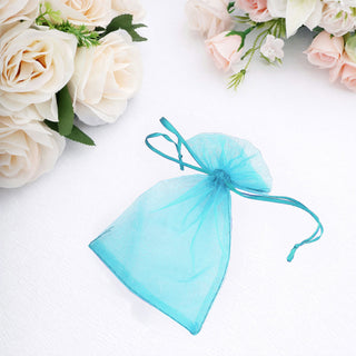 Blue organza gift bag tied with a ribbon, surrounded by soft floral decor.