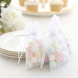 Pastel candy in sheer organza gift bags on white plates