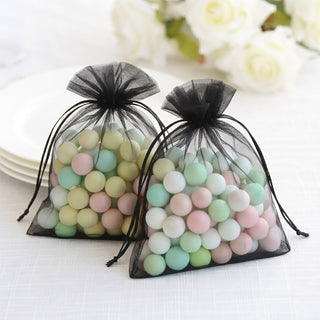 Colorful decorative candies in black organza bags on a white tablecloth.