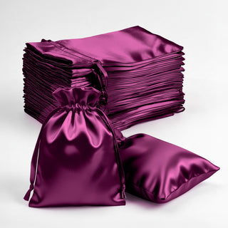 Stack of purple satin bags with one bag and cushion in front.