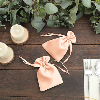 Peach satin favor bags tied with ribbons, styled with greenery and candles.