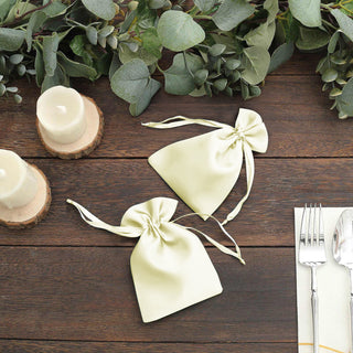 Decorative cream drawstring bags on a rustic wooden table with greenery.