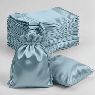Blue satin drawstring bags and pillows on a plain background.