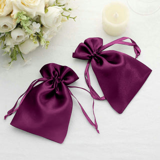 Purple satin drawstring bags on a white table with floral backdrop.