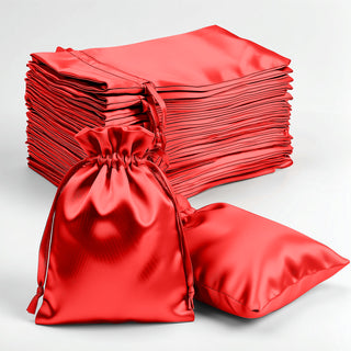 Red satin drawstring bags stacked and displayed on a plain background.