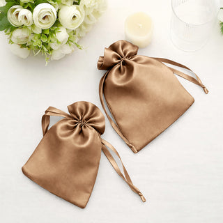 Two elegant brown satin drawstring bags on a light surface.