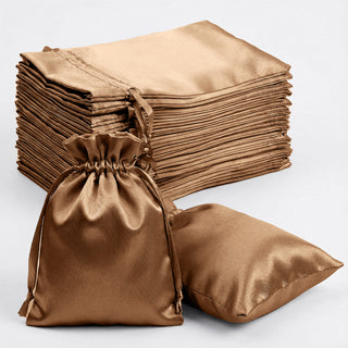 Stack of satin bags in bronze color, one bag and a pillow shown in the foreground.