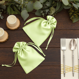 Green satin drawstring bags on a rustic table setting.