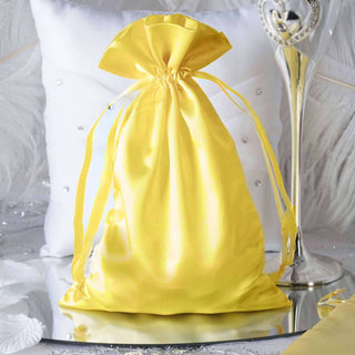 Yellow satin drawstring gift bag on a reflective surface.