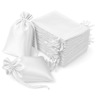 White satin drawstring bags and pouches stacked together on a plain background