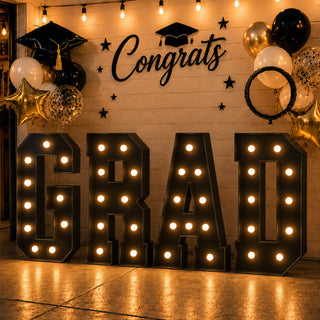 Graduation party backdrop with “GRAD” letters, balloons, and “Congrats” sign